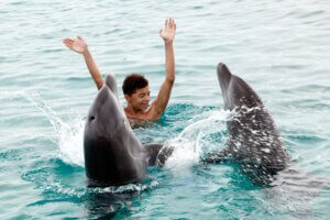 Chico nadando con delfines en cancun