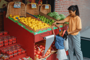 A mother and daughter shopping for fruit in a market